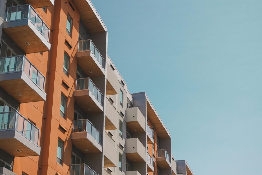 Contemporary apartment building with glass balconies under a clear blue sky.
